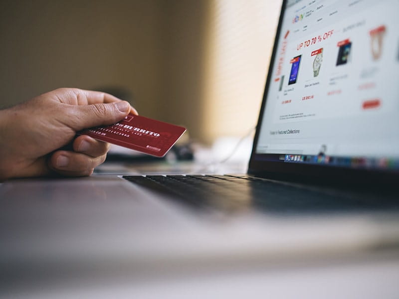 Person holding a credit card while shopping online on a laptop