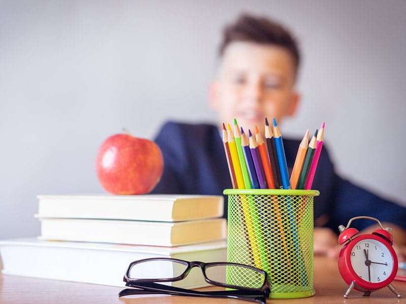 Stack of books with apple and school supplies representing school management system