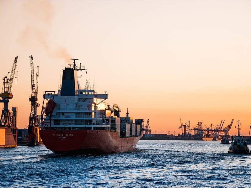 Cargo ship sailing at sunset representing maritime management and security